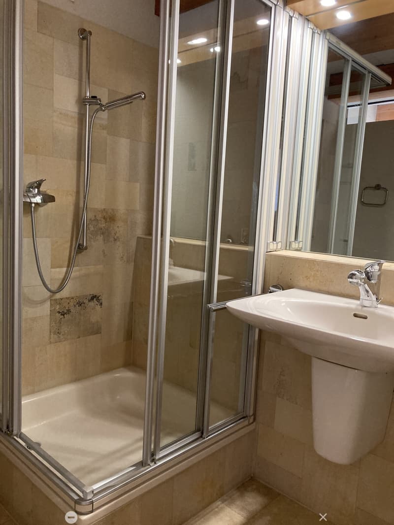 Modern bathroom with a bathtub, glass-enclosed shower, and a white sink with a chrome faucet.