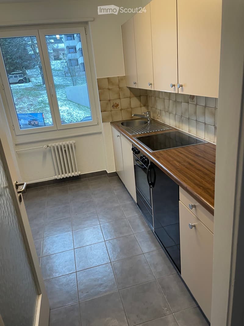 Modern kitchen with white cabinets, wooden countertops, and a stainless steel sink.