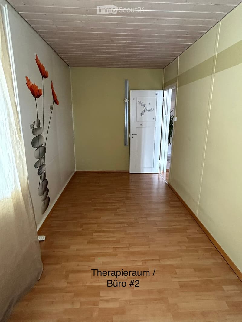 Empty hallway with wooden flooring, light-colored walls, and a white door at the end.