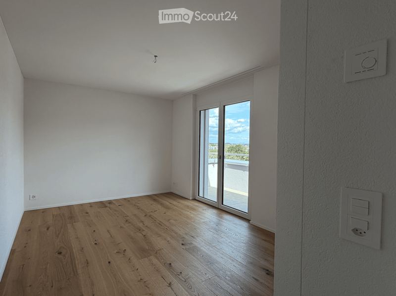 Unfurnished Room. Empty room with wooden flooring, white walls, and large sliding glass doors leading to a balcony.