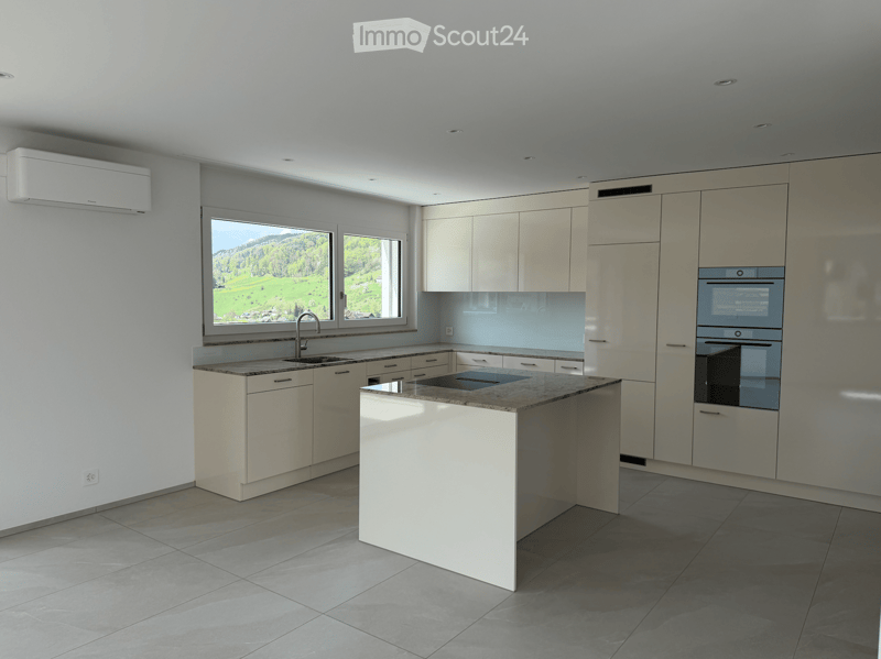 Kitchen. Modern kitchen with white cabinets, a central island, and a view of a green landscape through large windows.