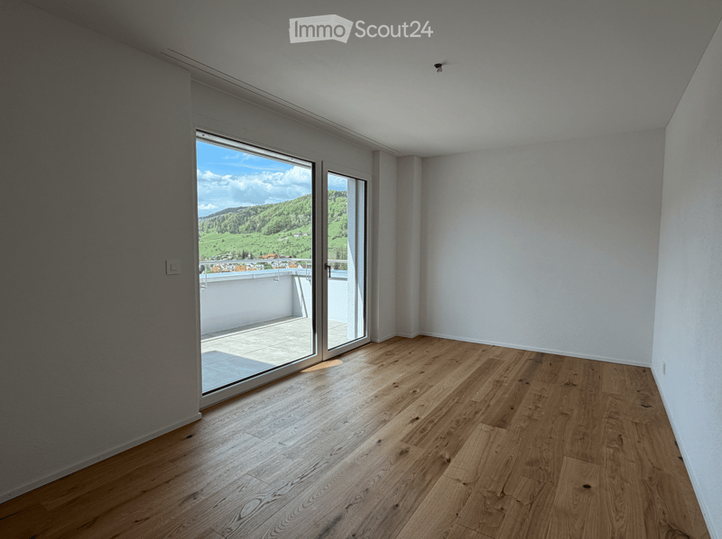 Unfurnished Room. Empty room with wooden flooring, white walls, and large sliding glass doors leading to a balcony with scenic mountain views.