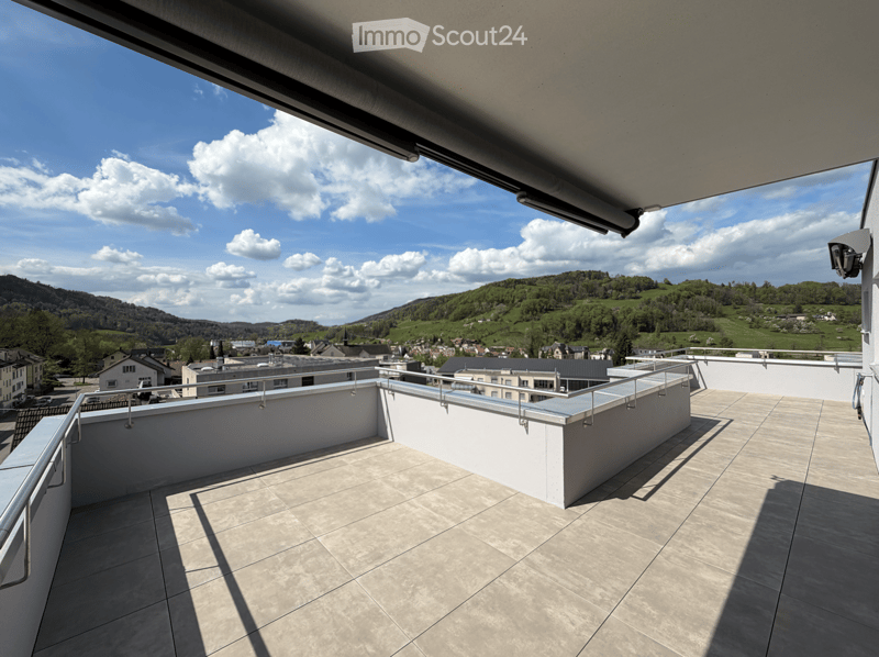 Balcony / Terrace. Roof terrace with tiled flooring, metal railings, and a scenic view of a town and surrounding hills under a partly cloudy sky.