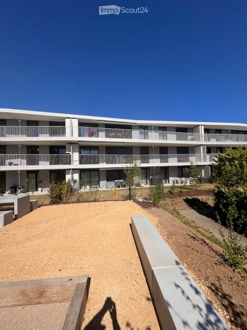 Modern multi-story residential building with multiple balconies and outdoor seating areas.