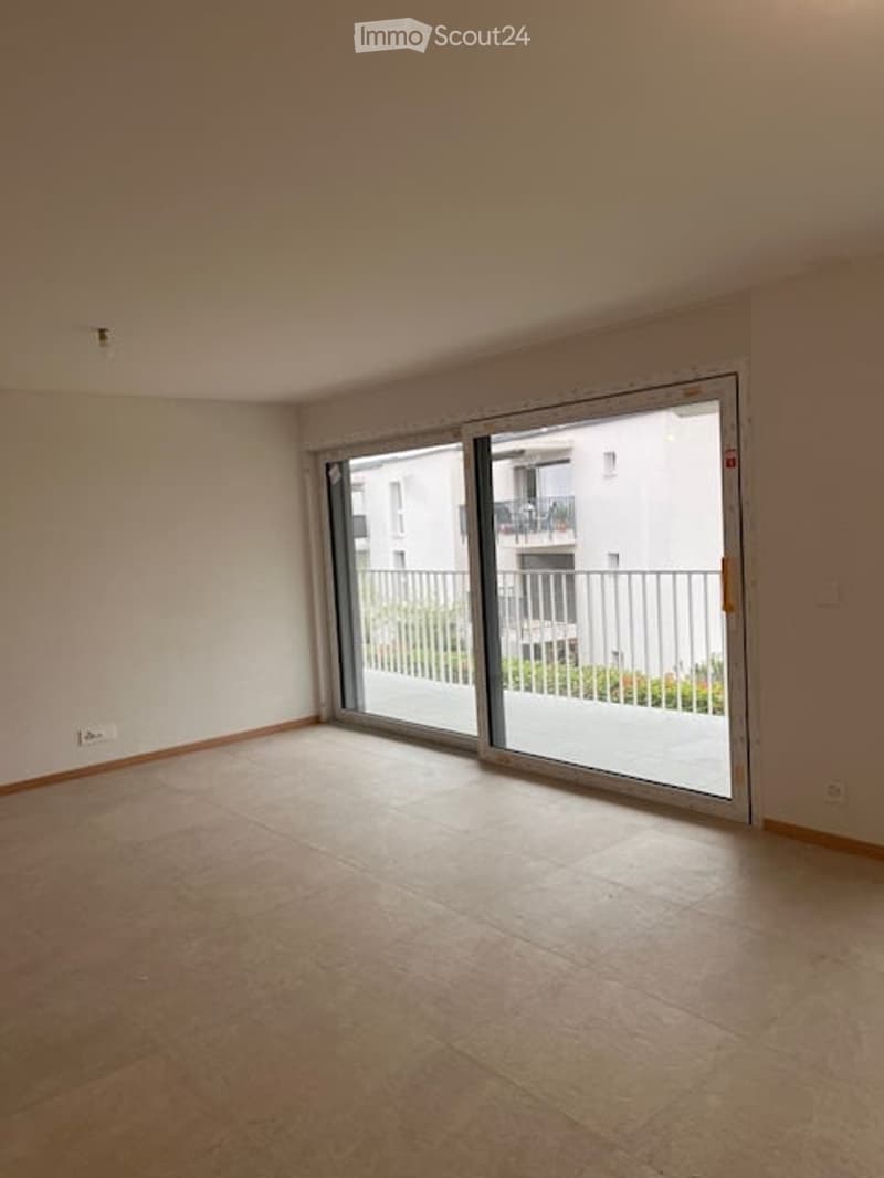 Empty room with large sliding glass doors leading to a balcony, tiled floor, and white walls.