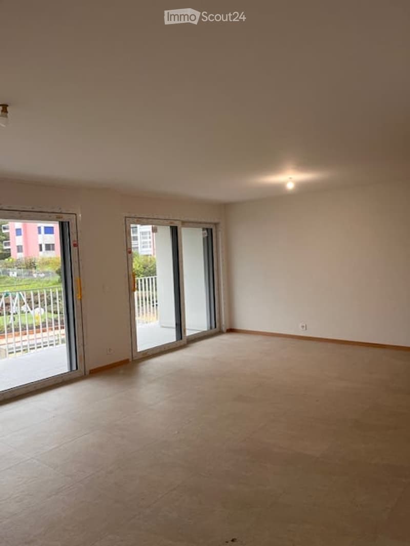 Empty room with large sliding glass doors leading to a balcony, light-colored tiled floor, and white walls.