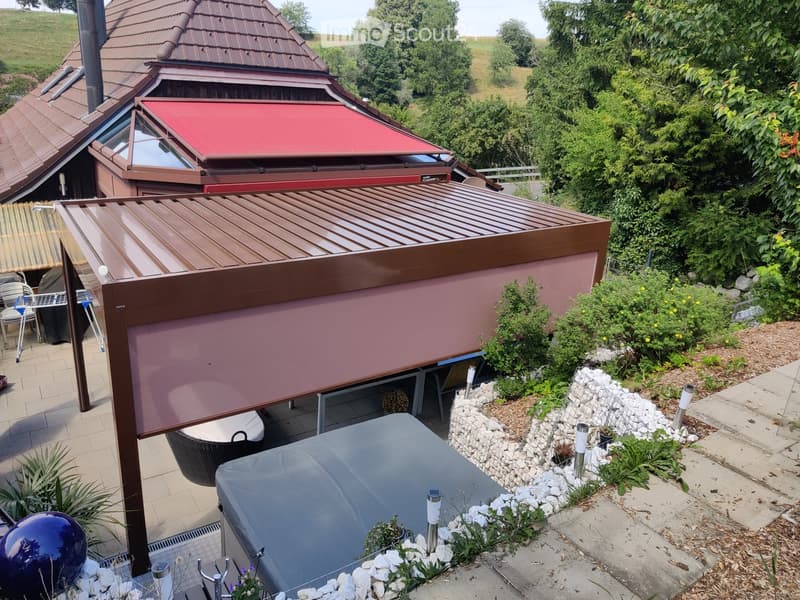 Garden with a covered patio, hot tub, outdoor furniture, and decorative elements like a blue sphere and plants.