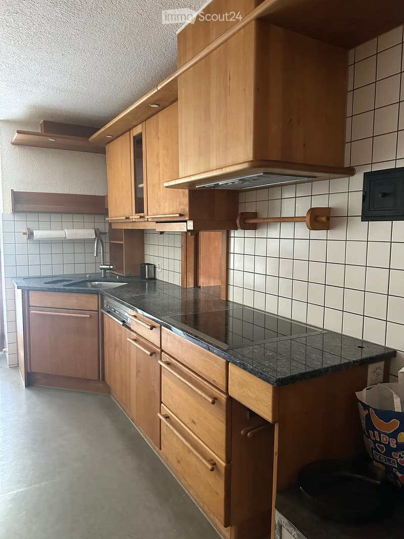 Modern kitchen with wooden cabinets, black countertop, stainless steel sink, microwave, and built-in oven.