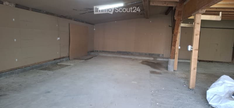 Empty basement space with concrete floor, exposed wooden beams, and unfinished walls.
