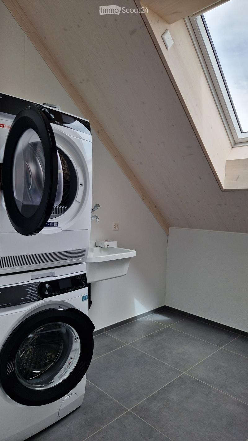 A small laundry room with a washing machine, dryer, sink, and power outlet.