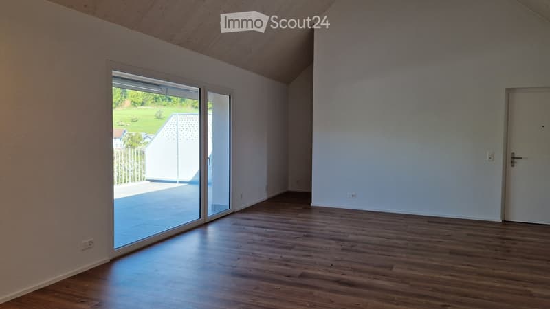 Empty room with wooden floors, white walls, and large glass doors leading to a balcony.
