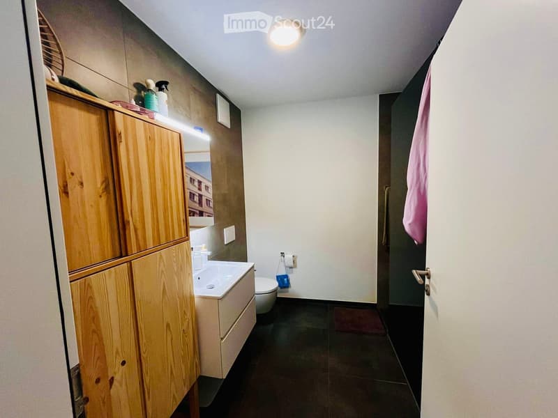 Bathroom with wooden cabinet, sink, toilet, mirror, and shower curtain.