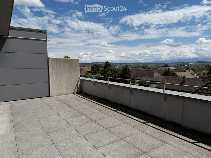 Roof terrace with concrete floor, metal railing, and scenic view of the town and mountains.