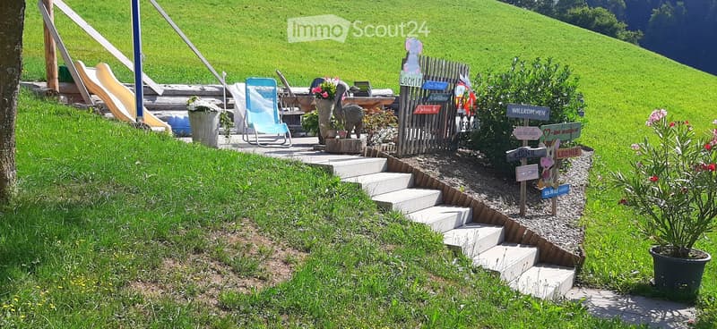 Garden area with steps, signs, a slide, a lounge chair, and potted plants.