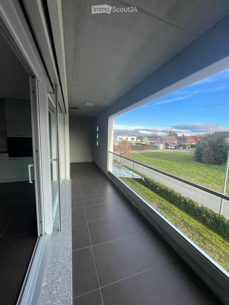 {"visible_features": ["Balcony / Terrace"],"type": "Balcony","description": "Spacious balcony with large windows overlooking a grassy area and residential buildings in the distance. The balcony has a concrete floor and a glass railing."}