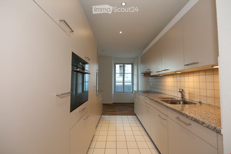 Modern kitchen with white cabinets, granite countertop, stainless steel sink, and built-in oven.