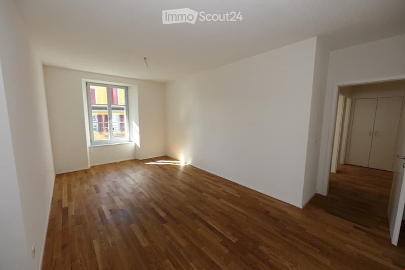 Empty room with wooden flooring, white walls, and a single window letting in natural light. No furniture or equipment is present.