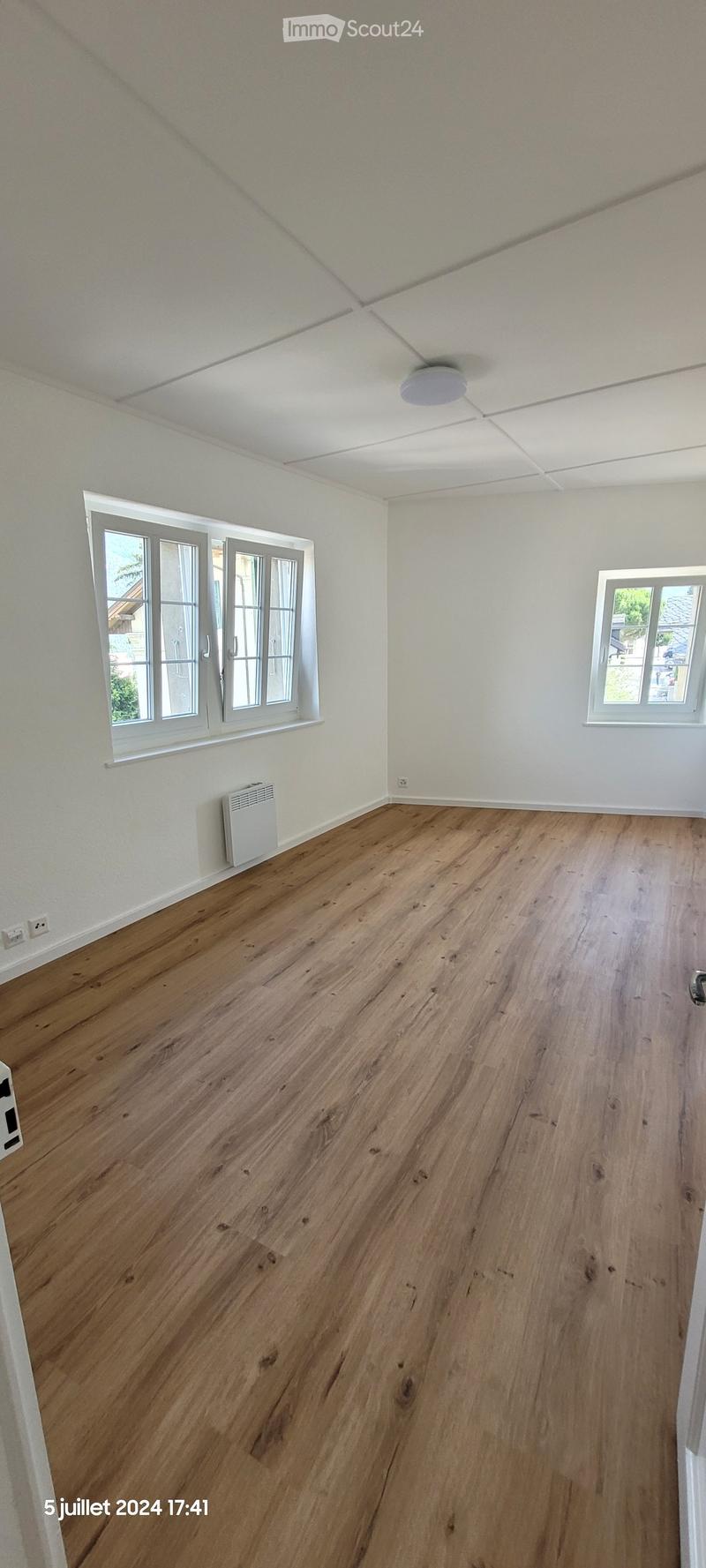 Empty room with wooden flooring, white walls, and large windows. No furniture or equipment present.