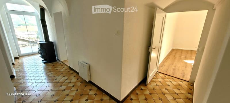 Hallway with tiled floor, fireplace, radiator, and open door leading to another room.