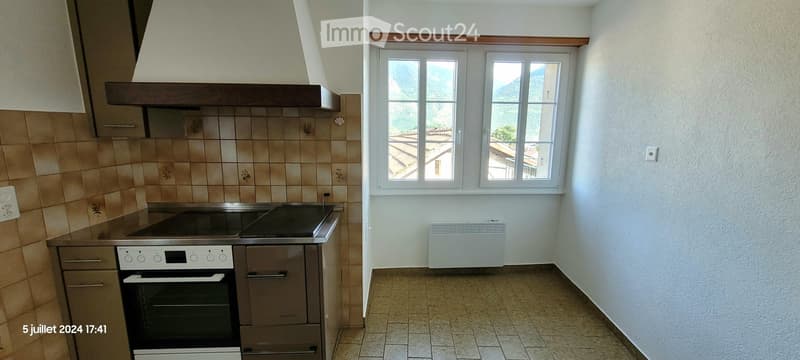 Modern kitchen with stainless steel appliances, tiled backsplash, and large windows overlooking a scenic view.