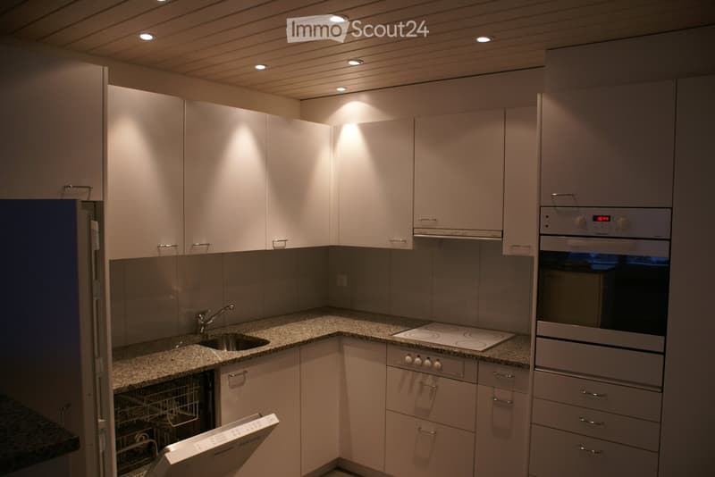Modern kitchen with white cabinets, granite countertops, stainless steel sink, and built-in appliances.