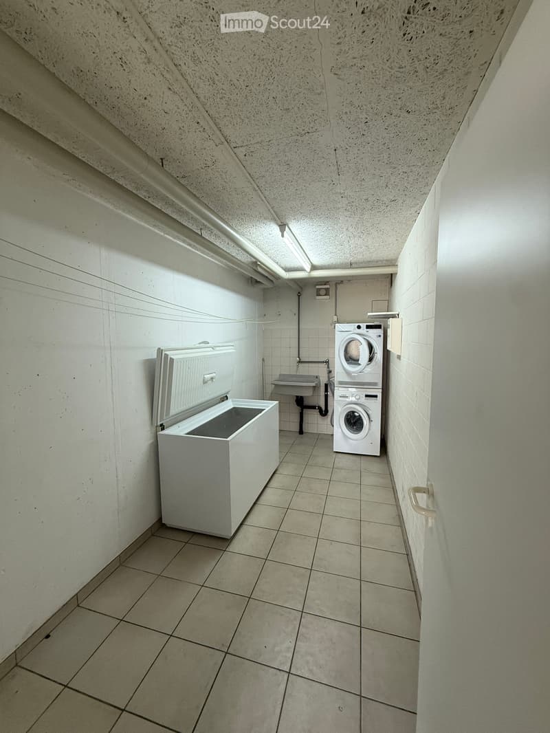 Utility room with tiled floor, white walls, washing machine, refrigerator, and sink.