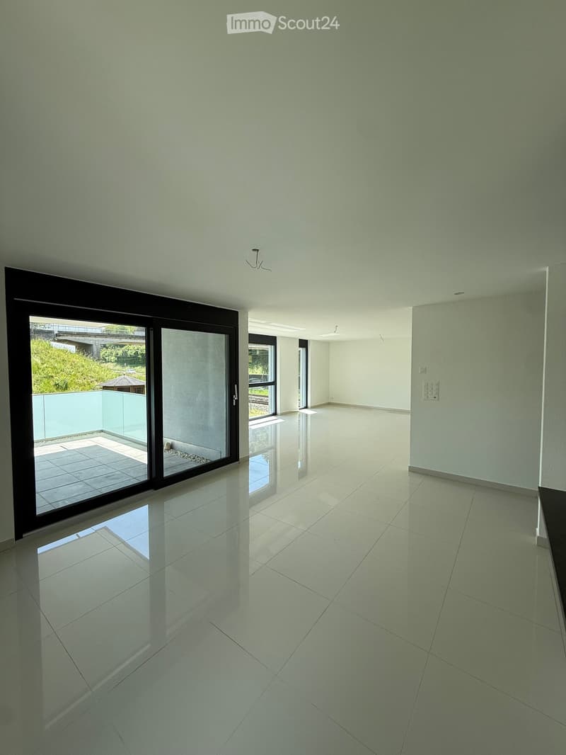 Empty room with white tiled floor, large sliding glass doors leading to a balcony, and white walls.