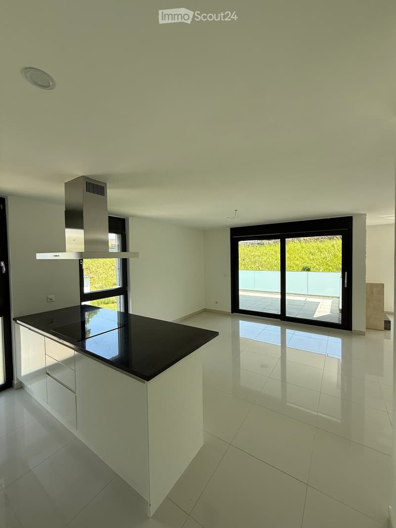 Modern, minimalist kitchen with white cabinets, black countertop, and large sliding glass doors leading to a balcony.