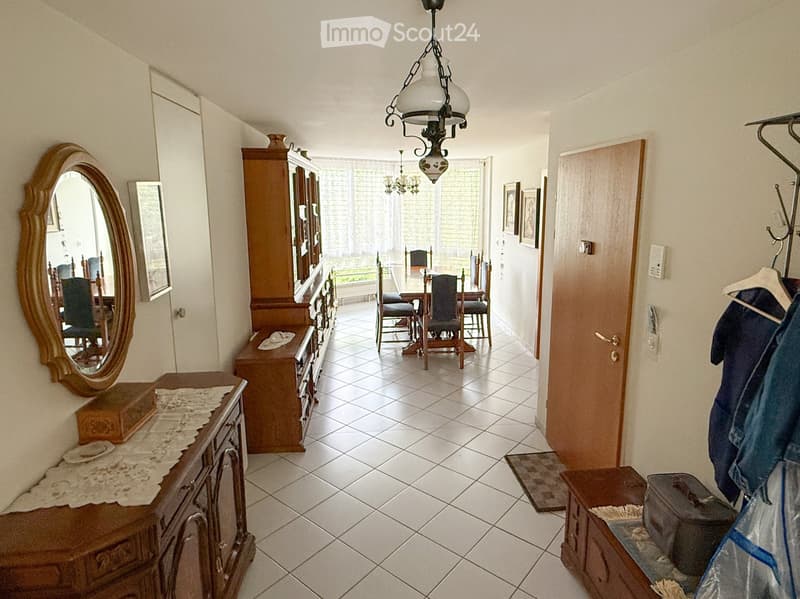 Hallway with tiled floor, wooden furniture, chandelier, and a view into a dining area with a table and chairs.