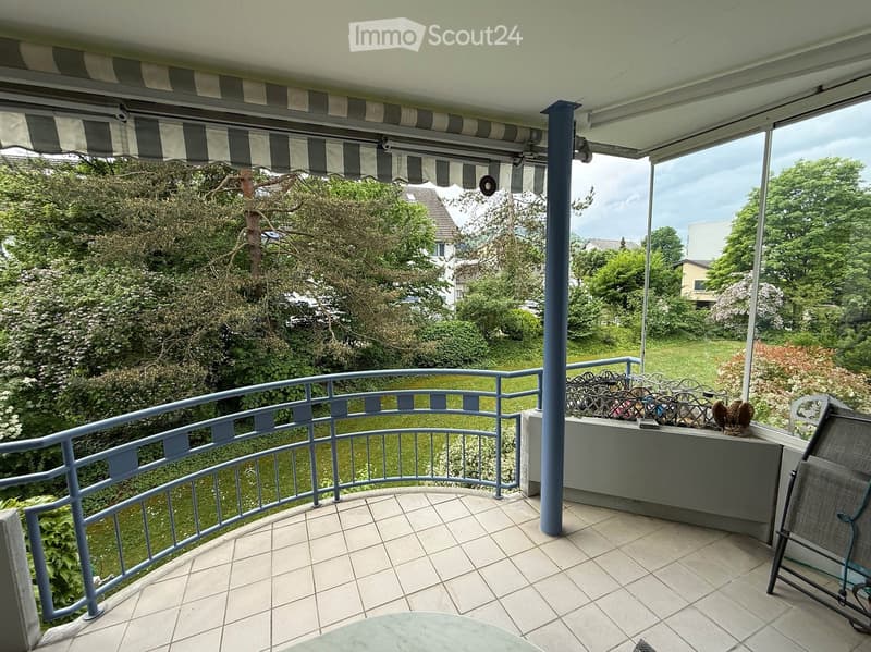 Balcony with tiled floor, metal railing, and outdoor furniture including a chair and small table.