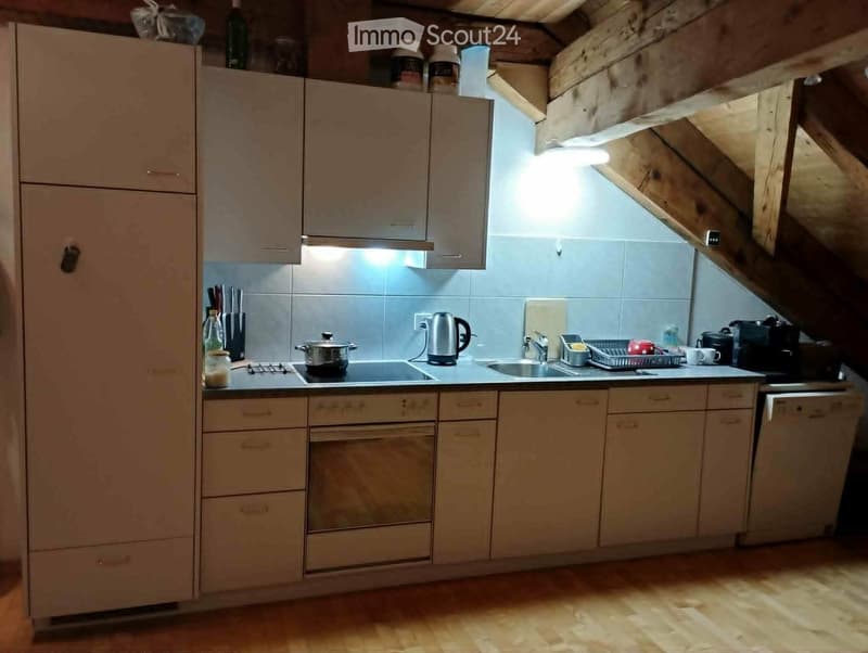 Modern kitchen with light wooden cabinets, stainless steel appliances, and a sleek countertop. Features include a sink, stove, oven, dishwasher, and coffee maker.