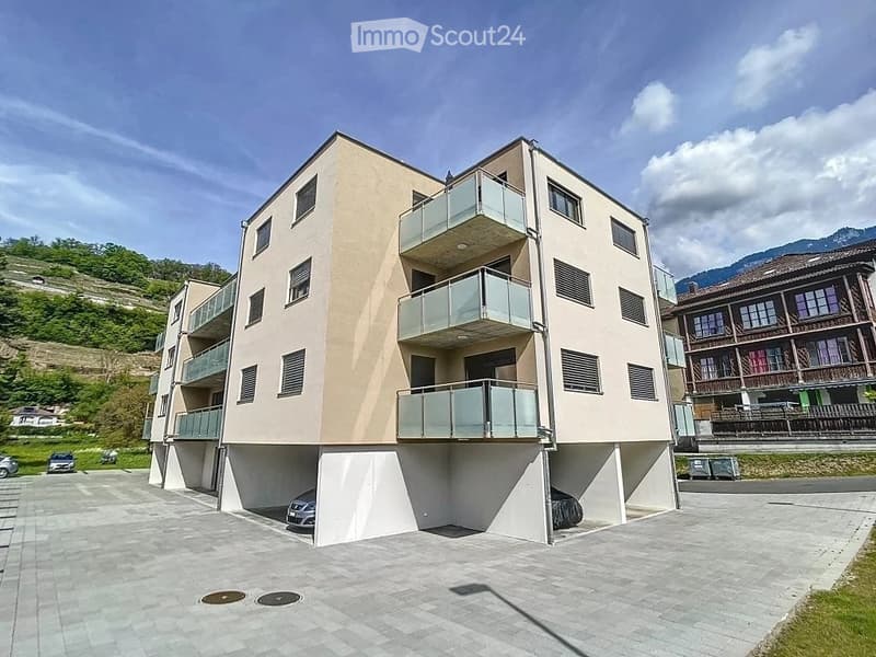 Modern multi-story building with balconies and a raised ground floor parking area.