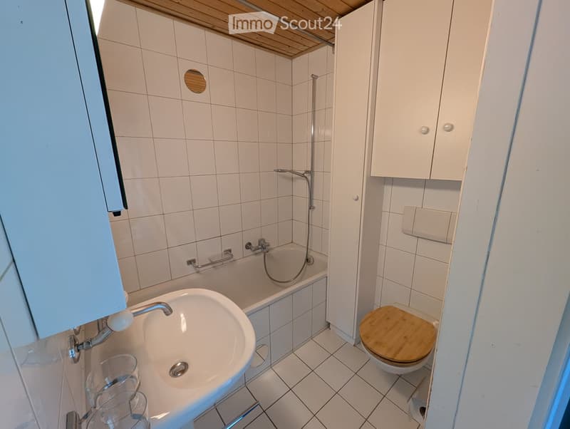 Bathroom with bathtub, toilet, sink, and white tiled walls and floor.