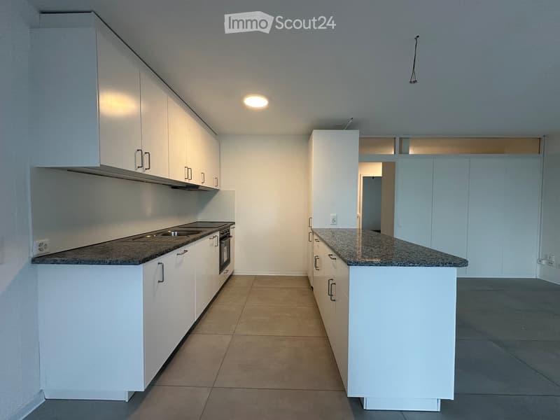 Empty kitchen with white cabinets, granite countertops, and stainless steel appliances.