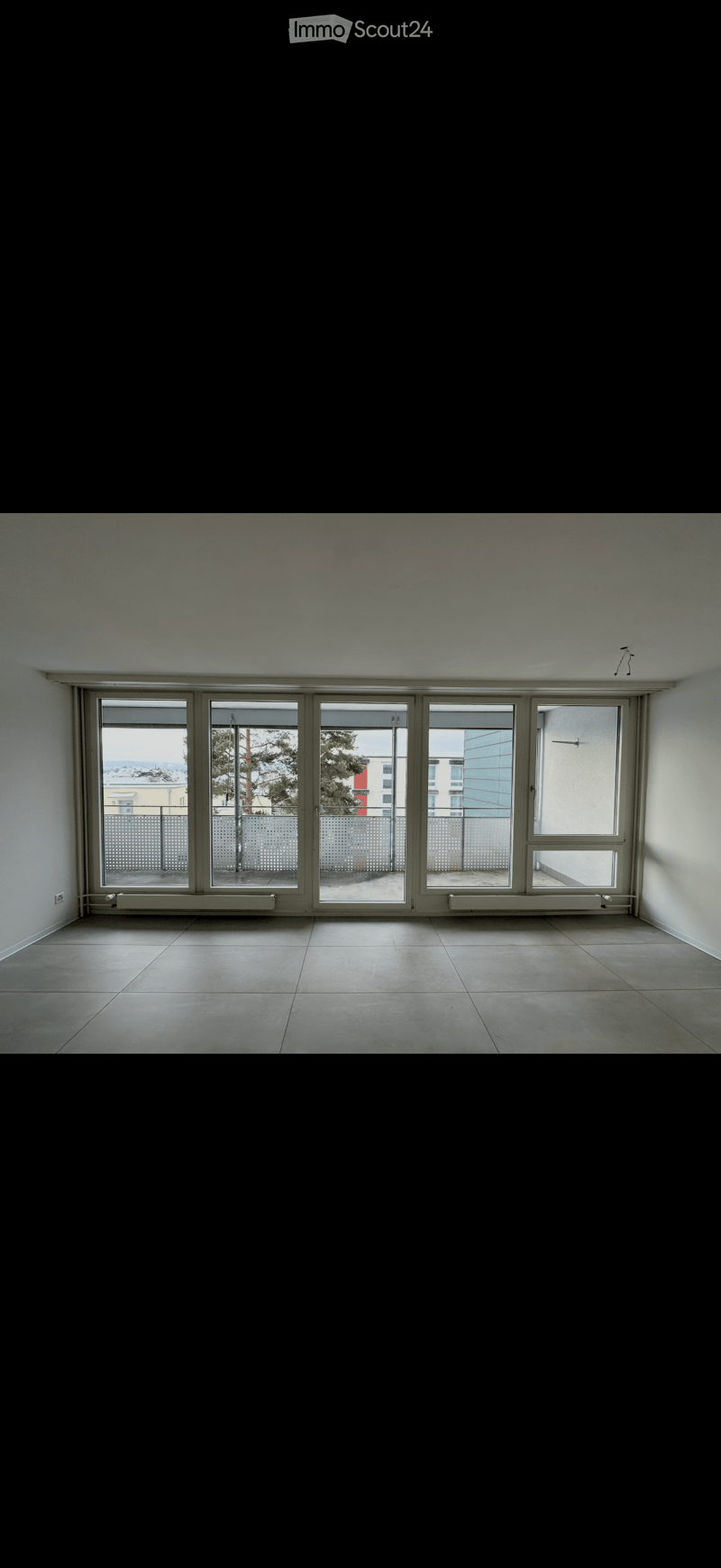 Empty room with large sliding glass doors leading to a balcony, tiled floor, and white walls.