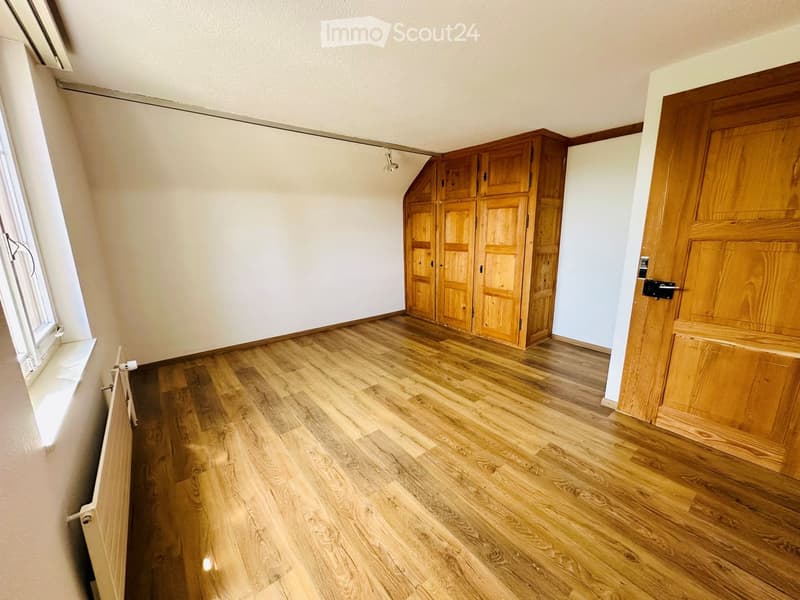 Empty room with wooden flooring, white walls, and wooden cabinetry. No furniture or personal items are present.