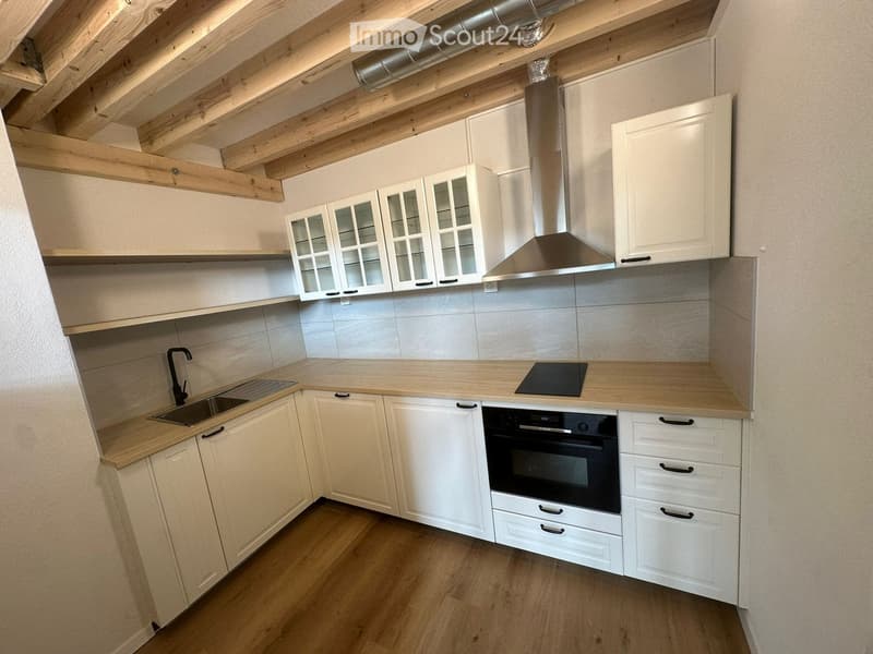 Modern kitchen with light wooden cabinets, stainless steel appliances, and a wooden countertop.