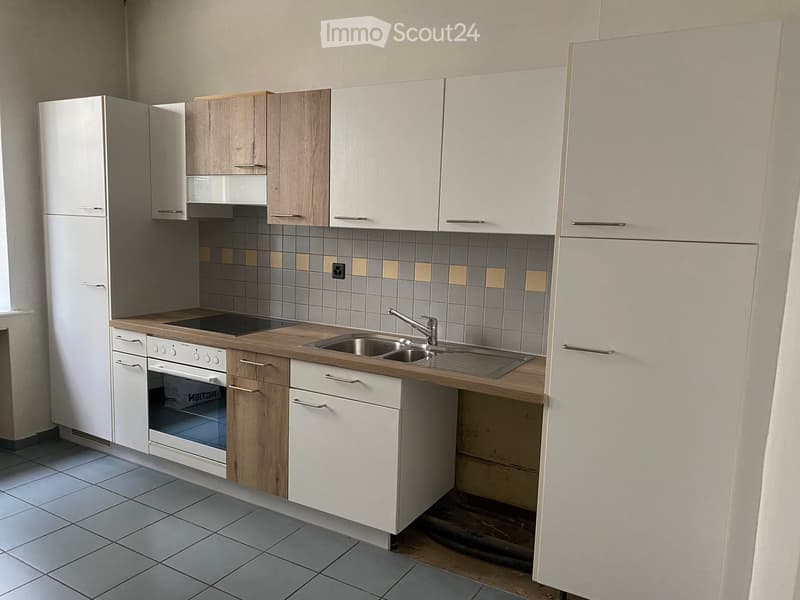 Modern kitchen with white cabinets, wooden countertops, stainless steel sink, and built-in appliances including a refrigerator and oven.