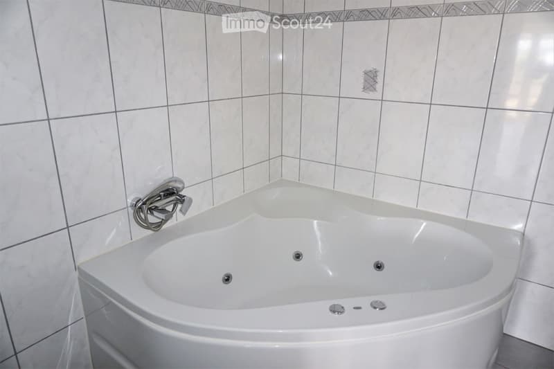 white corner bathtub with jets, silver faucet, white tiles