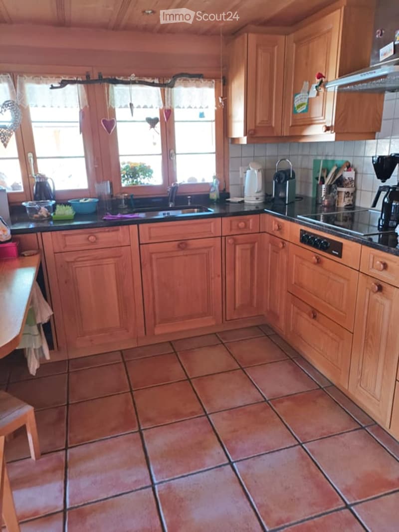 A cozy kitchen with wooden cabinets, tiled floor, and various appliances including a coffee maker and sink.