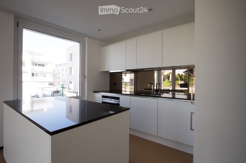 Kitchen. Modern kitchen with white cabinets, black countertops, and a large window overlooking a residential area.