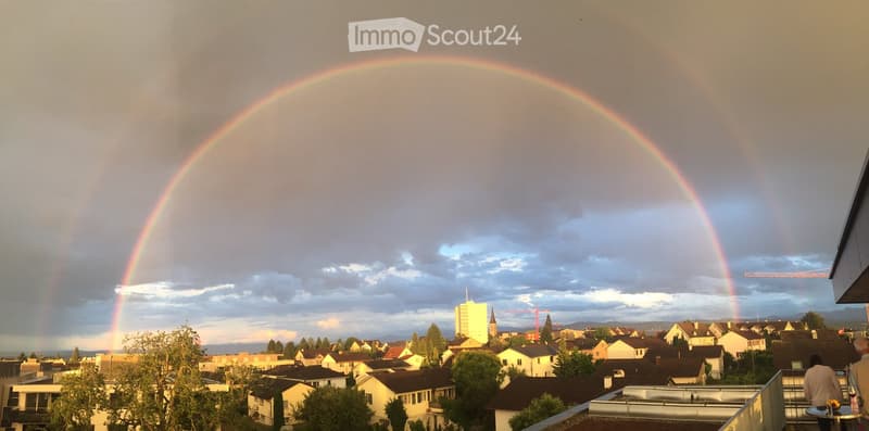 Balcony / Terrace. View from a balcony showing a double rainbow over a residential neighborhood with houses, trees, and distant mountains.