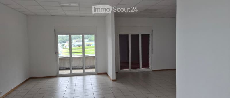 Empty room with white walls, tiled floor, and large glass doors leading to an outdoor area.