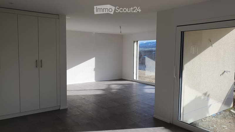 Empty room with tiled floor, white walls, large sliding glass door leading to outdoor area with mountain view.