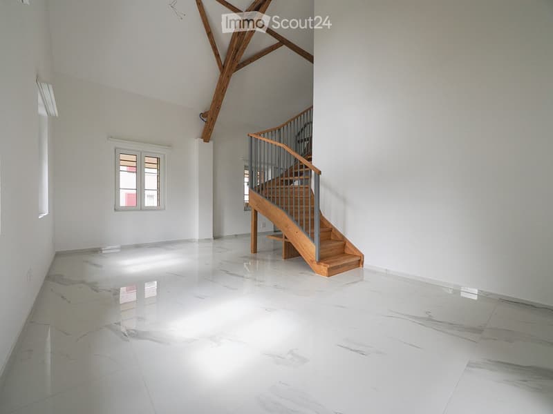 Empty room with white walls, polished marble floor, and a wooden staircase leading upwards.