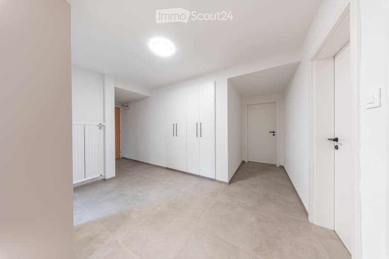 Empty hallway with white walls, tiled floor, built-in white closet, and doors leading to other rooms.