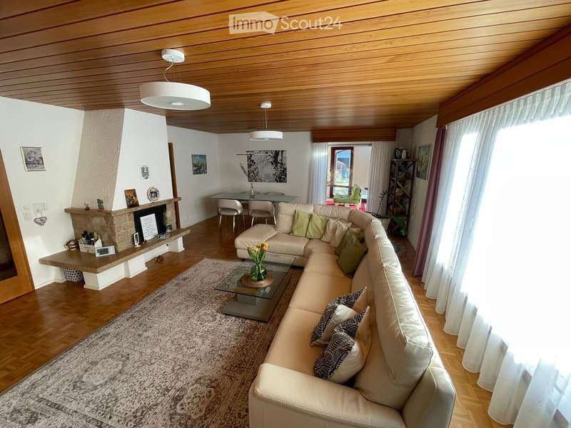 Modern living room with a sectional sofa, glass coffee table, dining area, fireplace, and large windows with curtains.