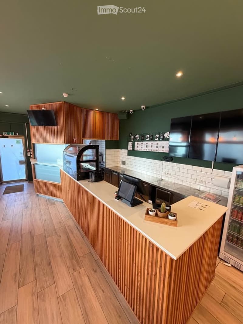 Modern kitchen area with wooden cabinets, a central counter, display case, and small decorative items.