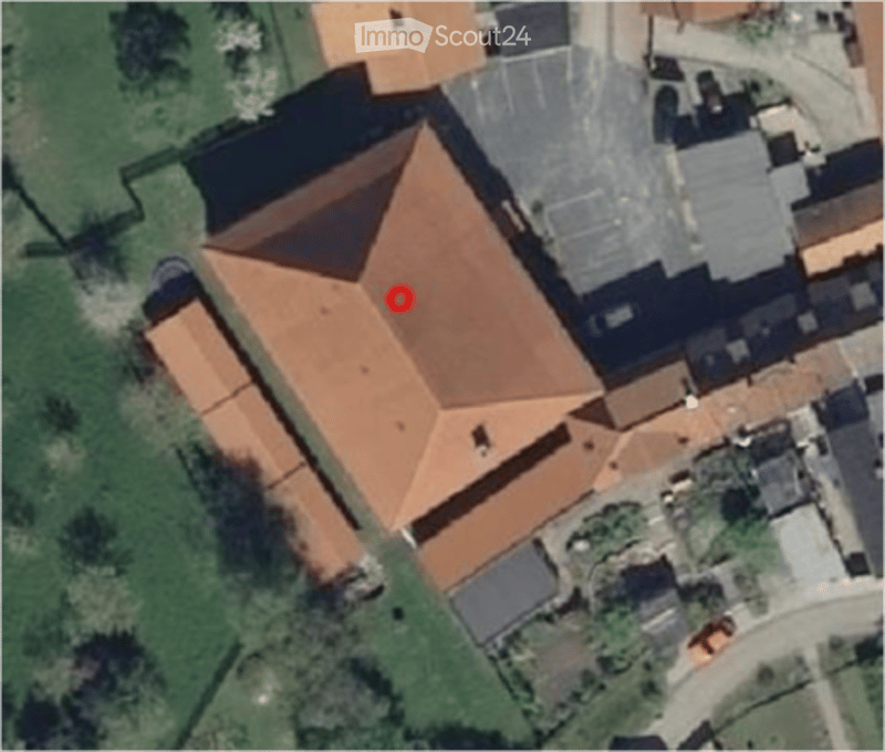 Aerial view of a residential building with a red-tiled roof and surrounding greenery.