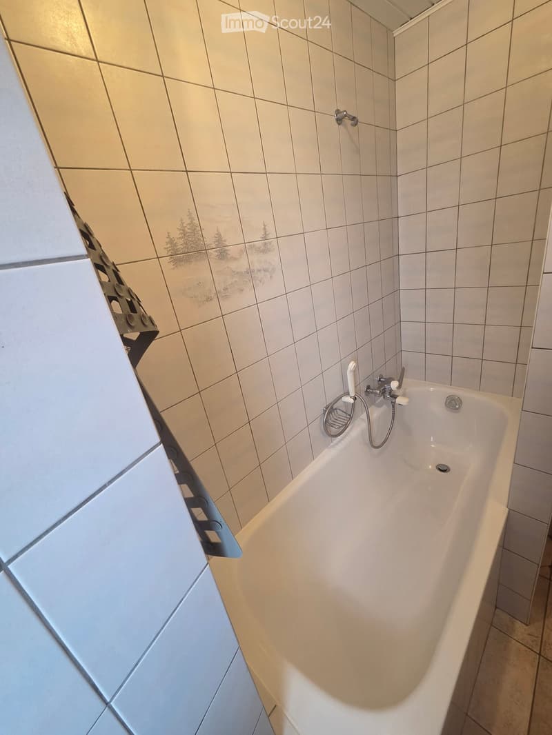 Bathroom. Bathroom with a white bathtub, tiled walls, and a showerhead attached to the wall.
